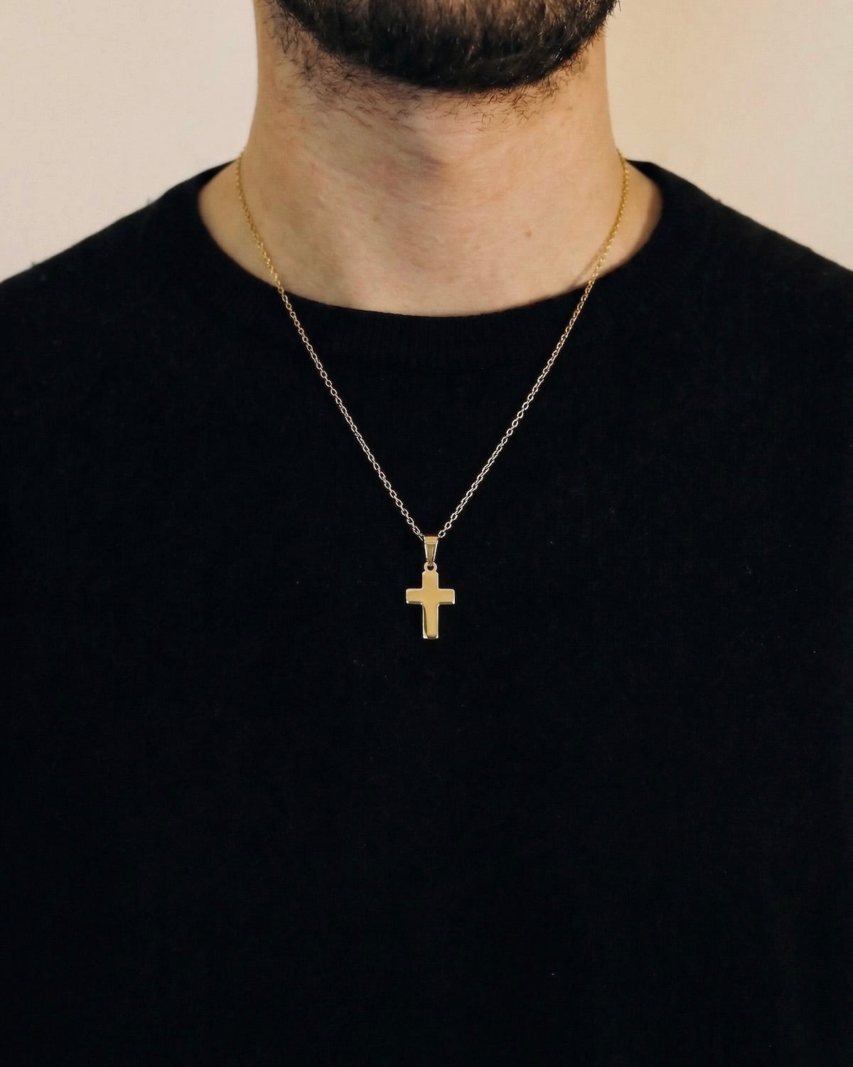 Man wearing a gold cross necklace on a 50cm chain over a black t-shirt