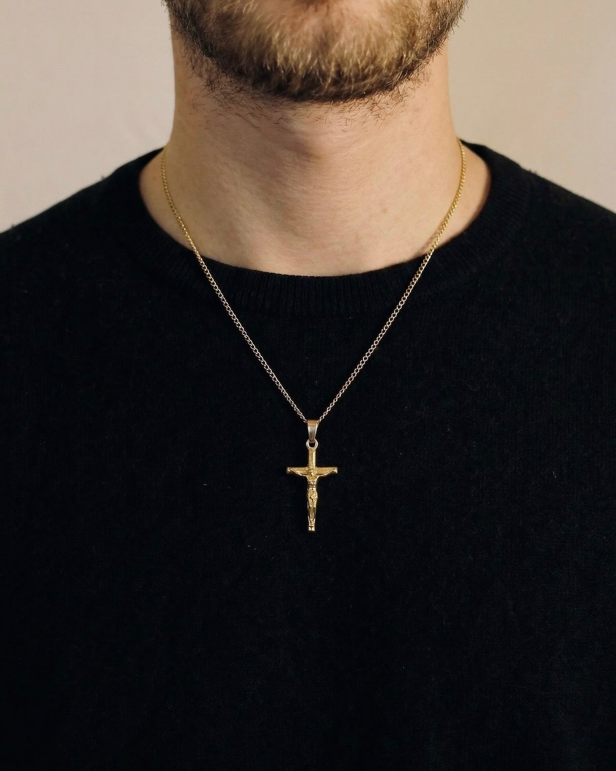 Man wearing a gold crucifix necklace on a 50cm chain over a black t-shirt