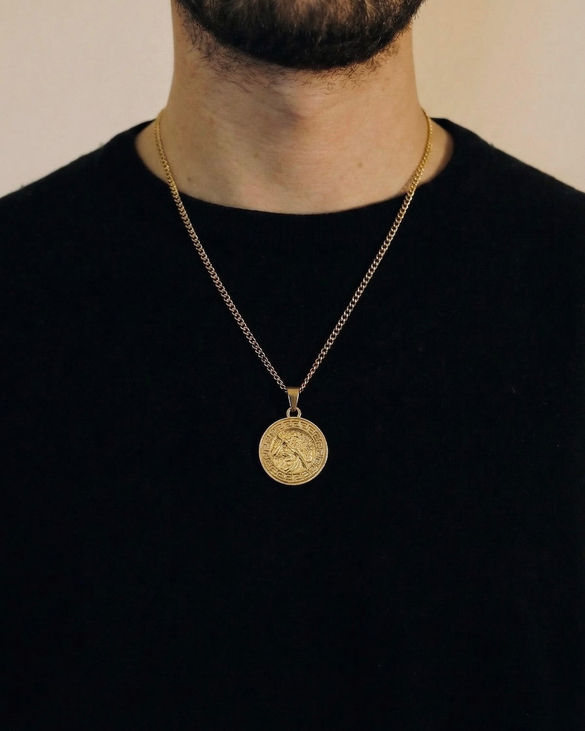 Man wearing a gold Greek Zeus necklace on a 50cm chain over a black t-shirt
