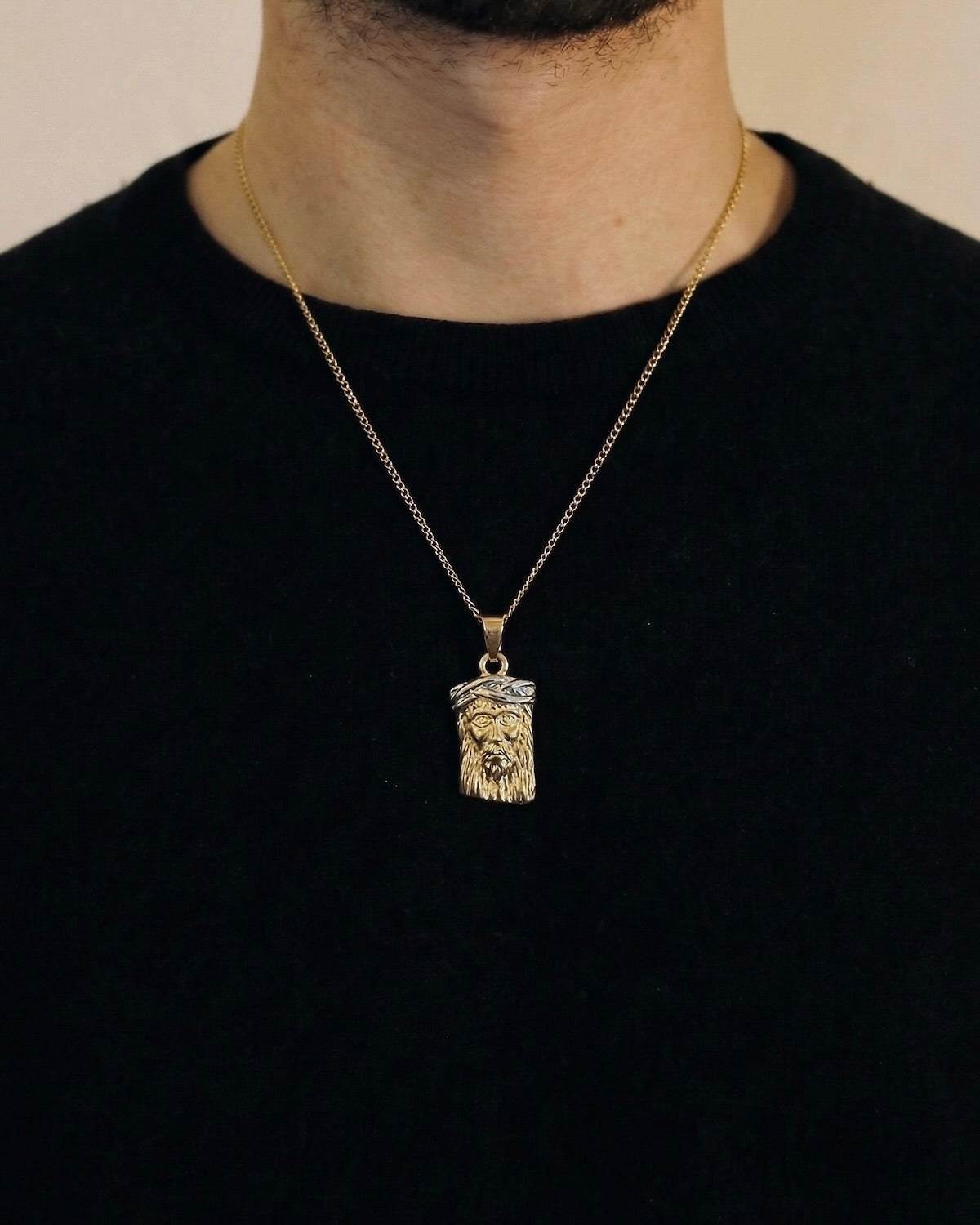 Man wearing a gold Jesus head necklace on a 50cm chain over a black t-shirt