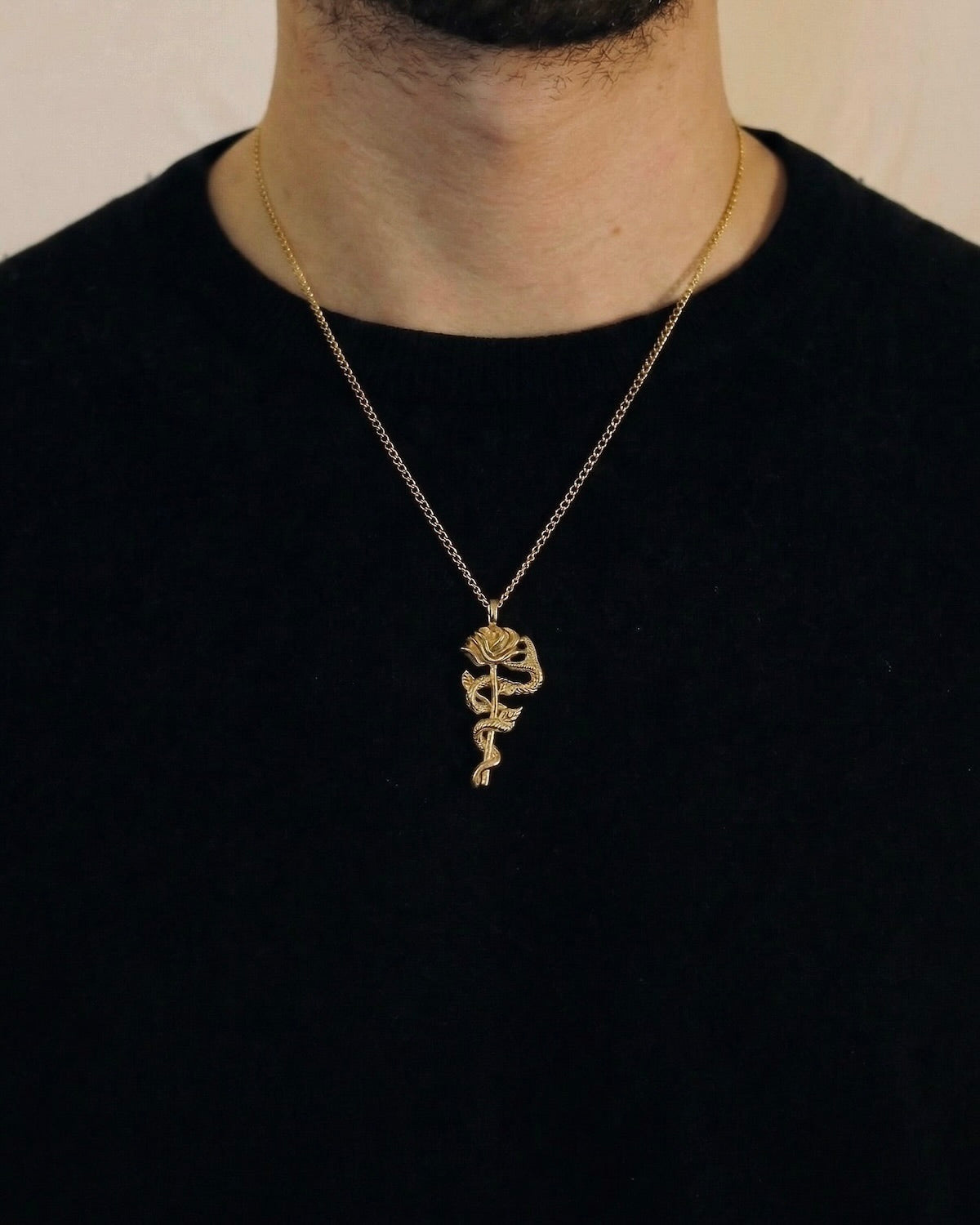Man wearing a gold snake rose necklace on a 50cm chain over a black t-shirt
