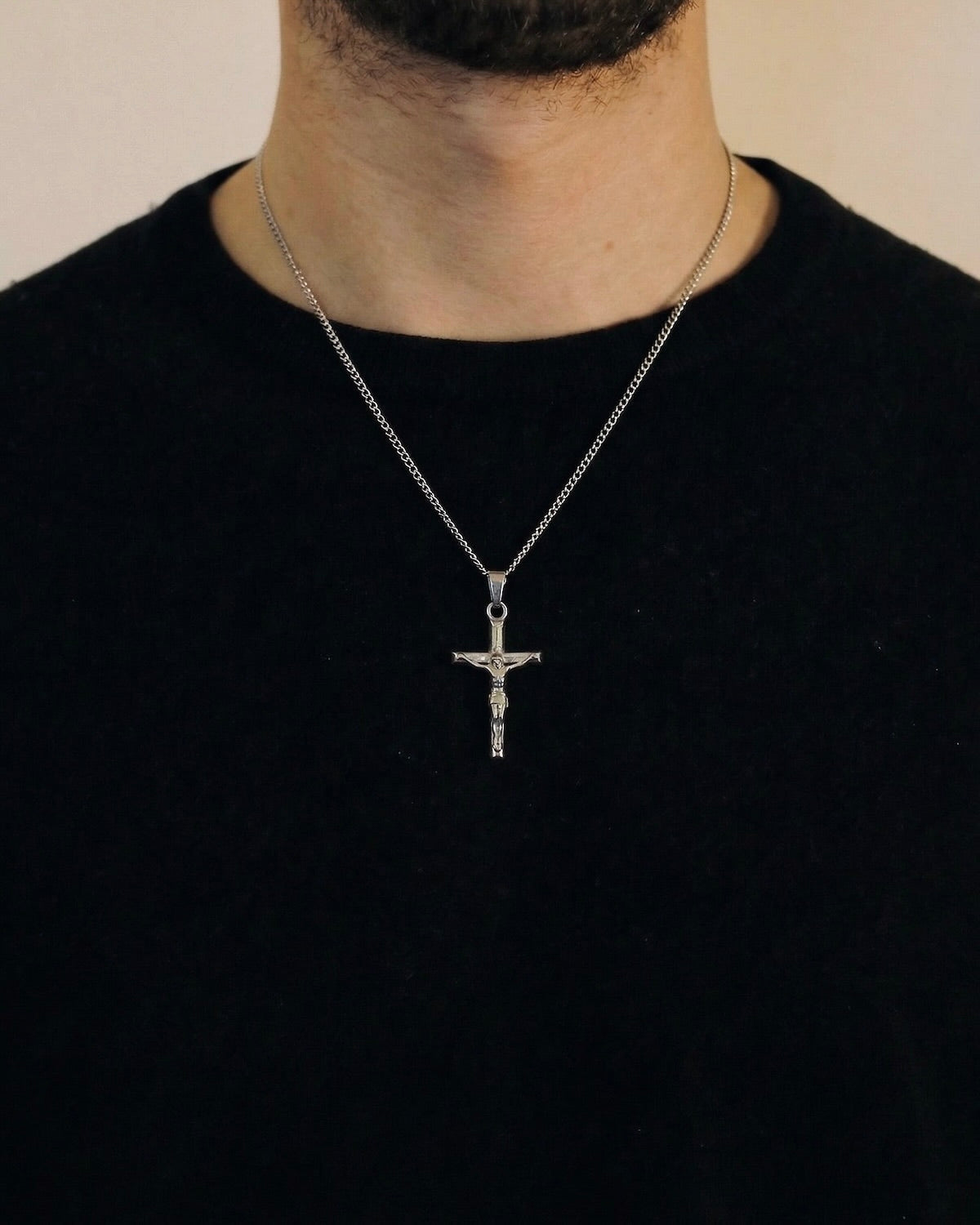 Man wearing a silver crucifix necklace on a 50cm chain over a black t-shirt