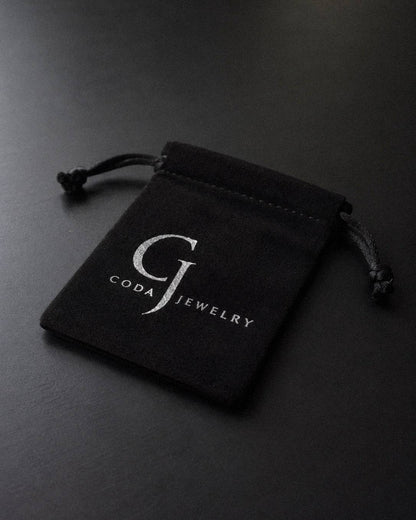 A small black velvet jewelry pouch with a drawstring closure, featuring the 'GODA JEWELRY' logo printed in white on the front, set against a dark gray background.