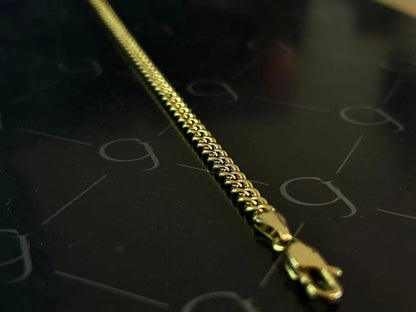 4mm gold Cuban link chain with lobster clasp on a dark background