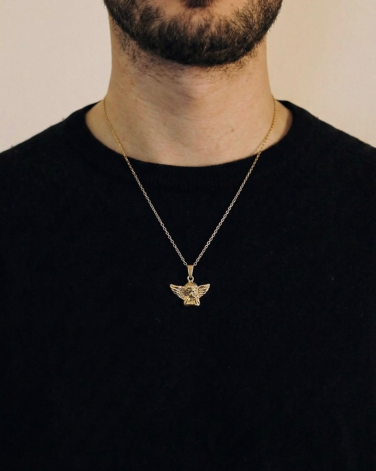Man wearing a gold angel necklace on a 50cm chain over a black t-shirt