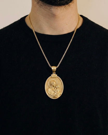 Man wearing a gold baby Jesus necklace on a 50cm chain over a black t-shirt