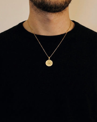 Man wearing a gold compass necklace on a 50cm chain over a black t-shirt