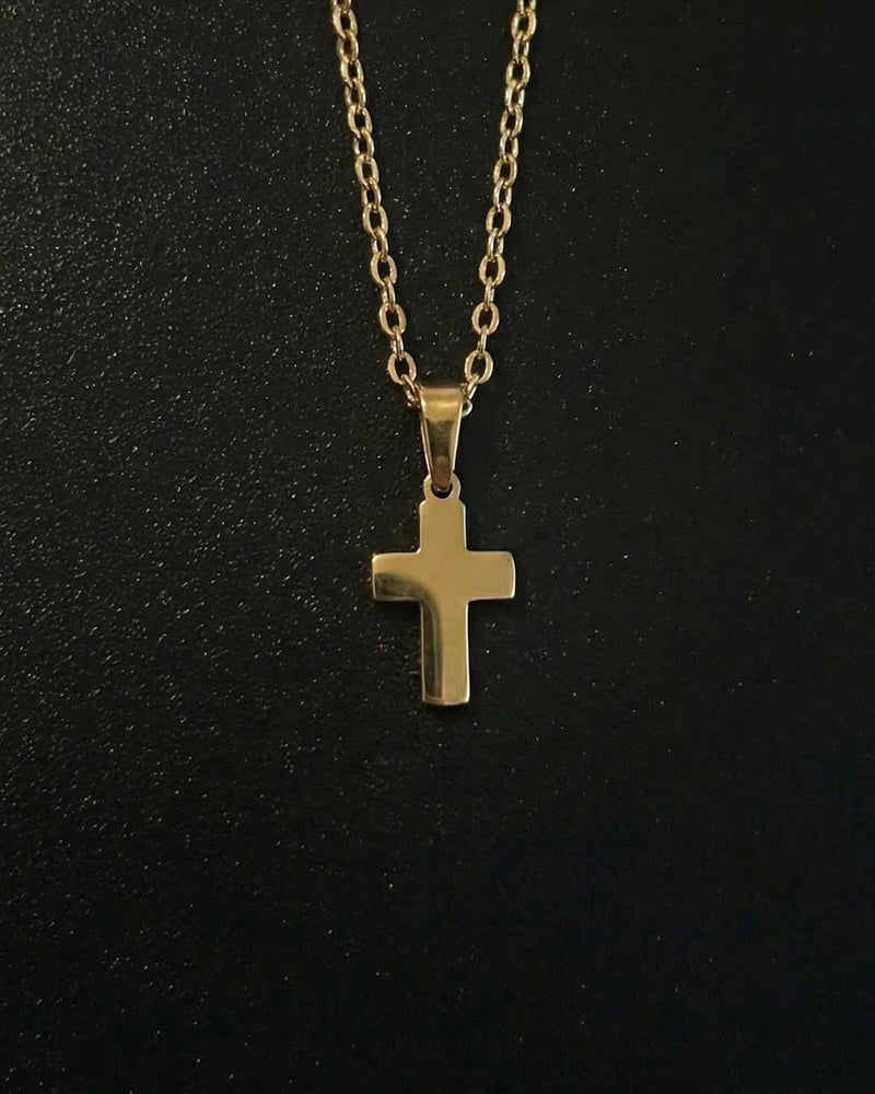 Gold cross pendant in a compact size with a polished mirror finish, close detail