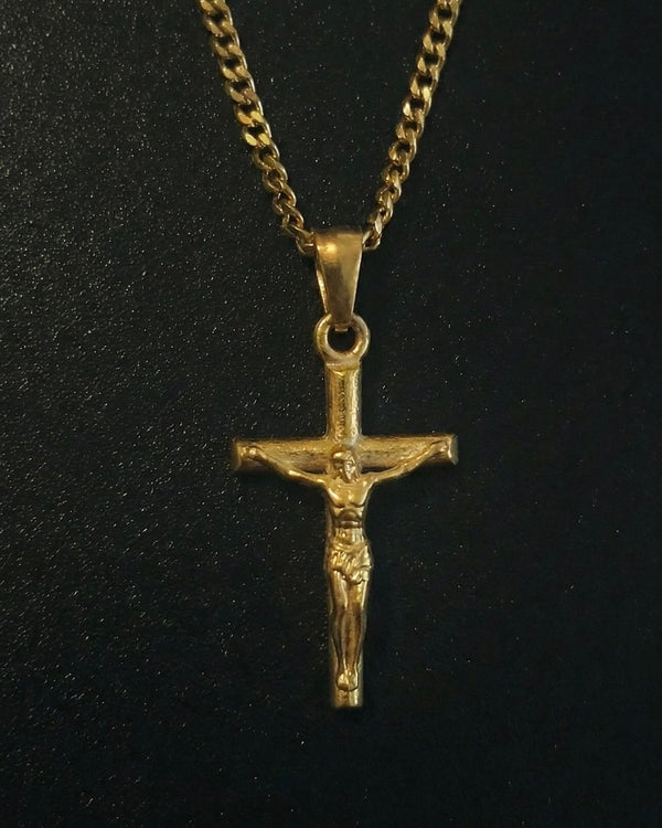 Gold crucifix pendant with the figure of Christ on a slim cross, close detail