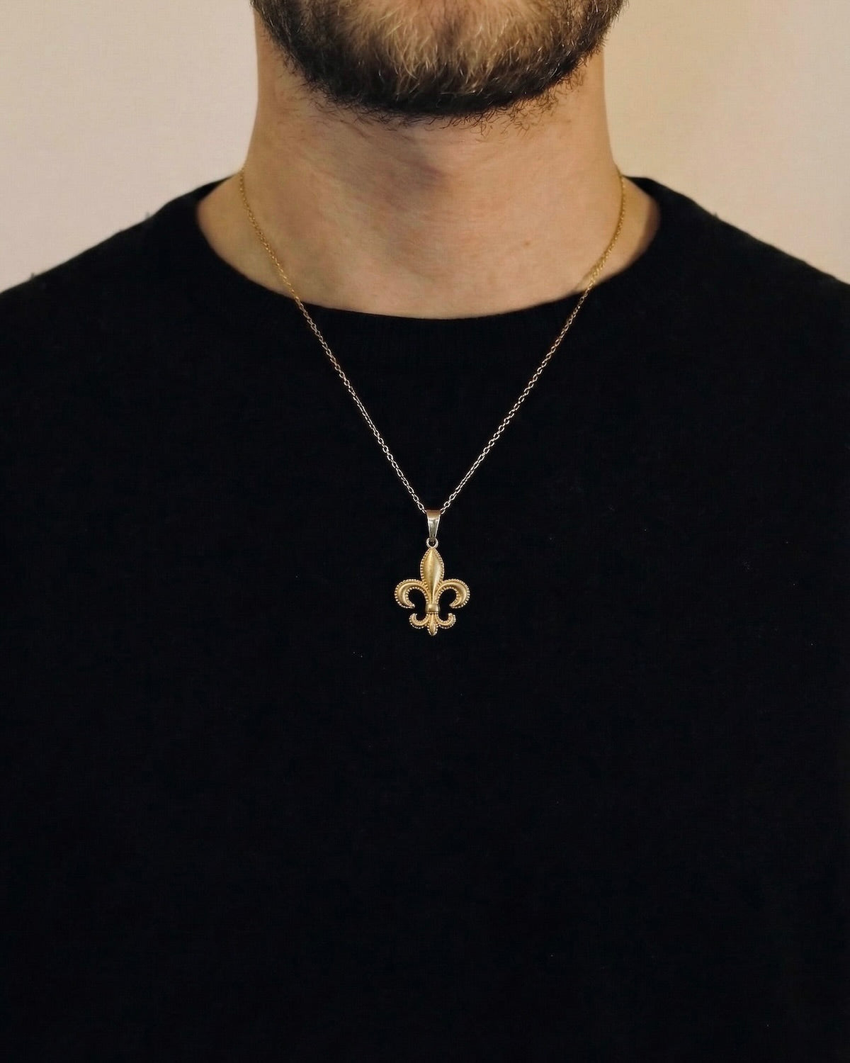 Man wearing a gold fleur-de-lis necklace on a 50cm chain over a black t-shirt