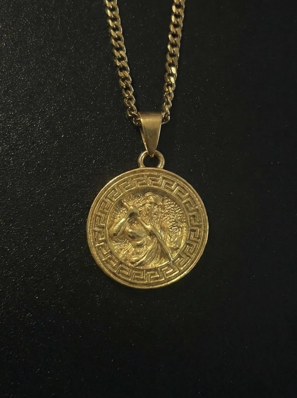 Gold Greek Zeus pendant with a bearded Zeus figure and Greek key border, close detail
