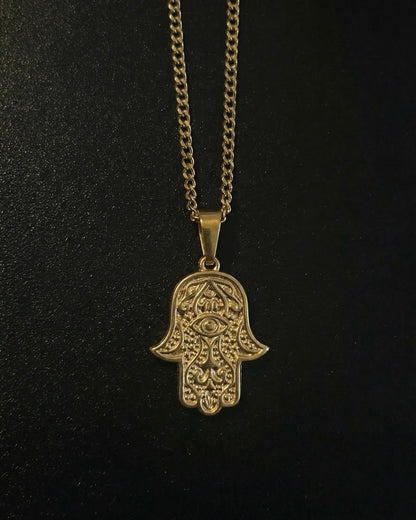 Gold hamsa evil eye pendant with an eye in the centre of the palm and beaded detailing, close detail