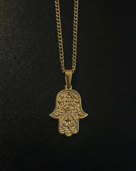 Gold hamsa evil eye pendant with an eye in the centre of the palm and beaded detailing, close detail