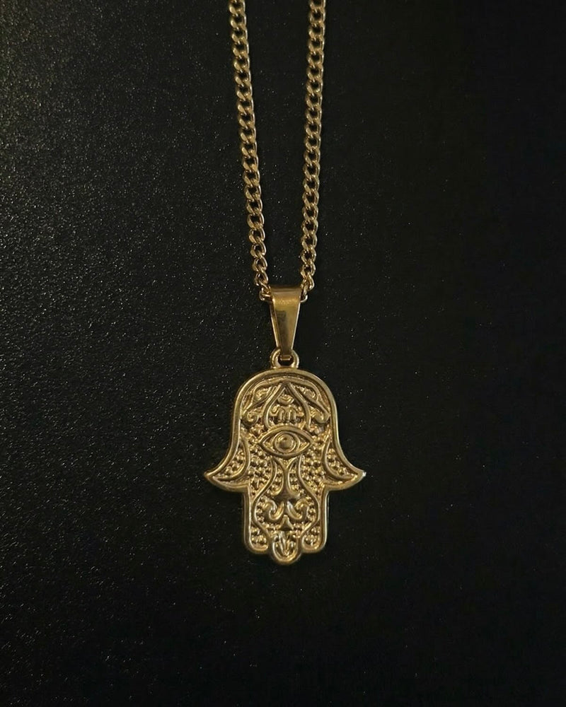 Gold hamsa evil eye pendant with an eye in the centre of the palm and beaded detailing, close detail