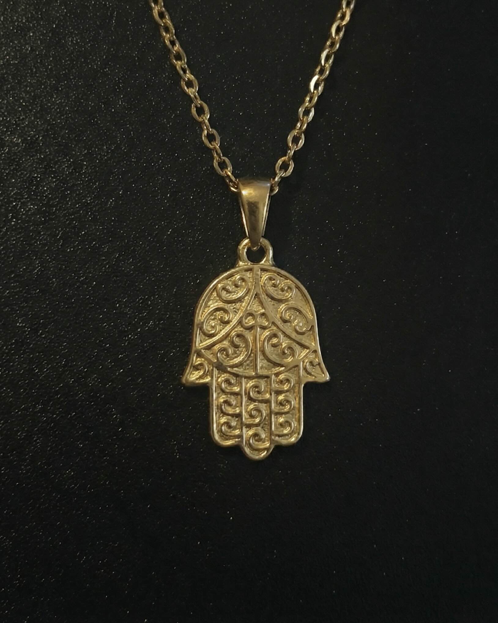 Gold hamsa hand pendant with detailed filigree scrollwork, close detail