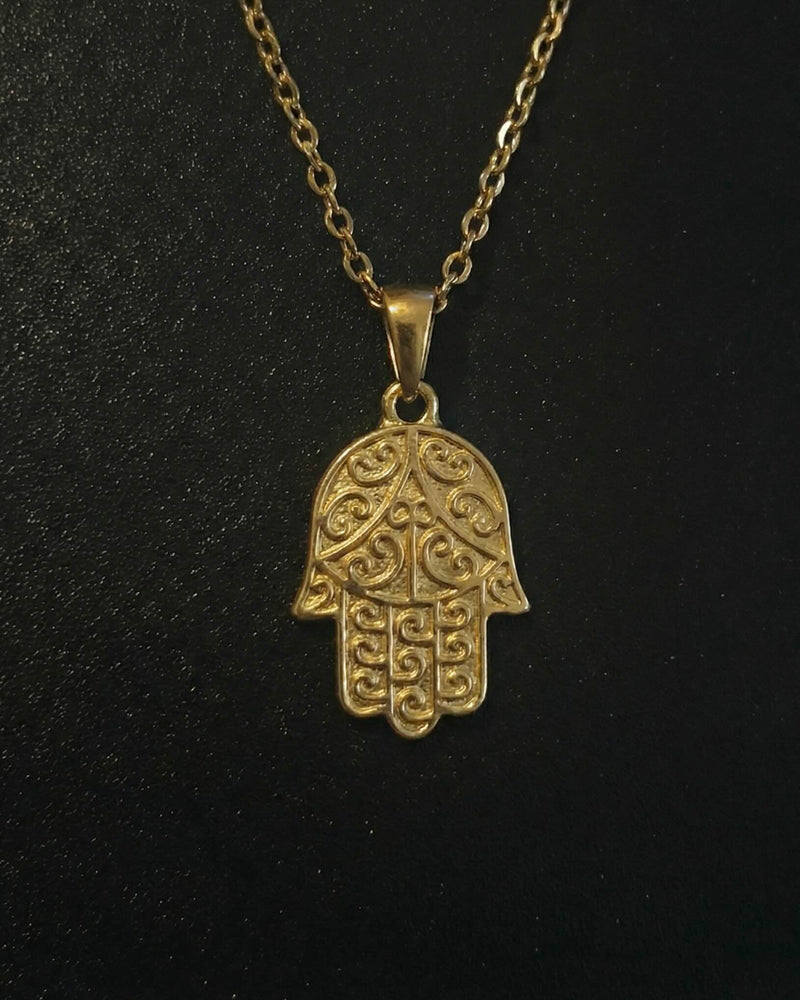 Gold hamsa hand pendant with detailed filigree scrollwork, close detail