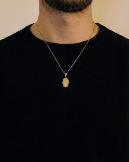 Man wearing a gold hamsa hand necklace on a 50cm chain over a black t-shirt