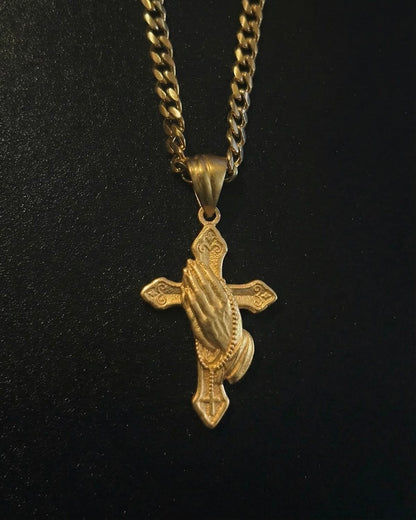 Gold hand cross pendant with sculpted praying hands over an ornate cross, close detail