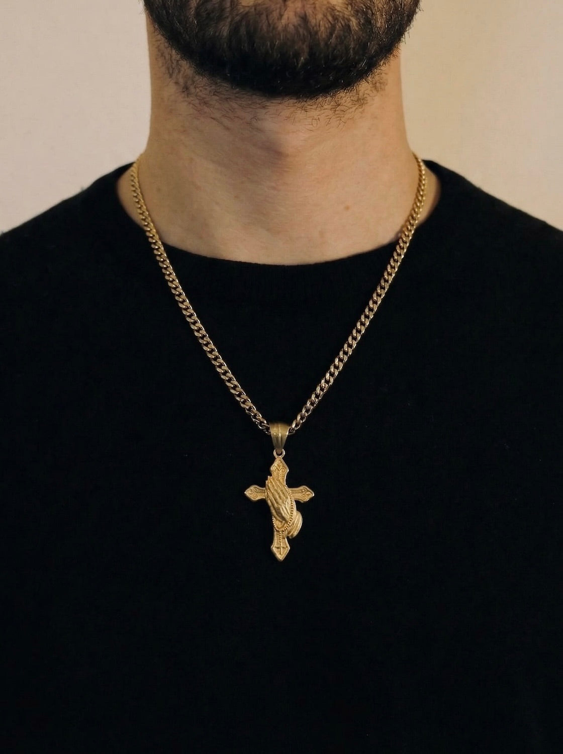 Man wearing a gold praying hands cross necklace on a 50cm chain over a black t-shirt