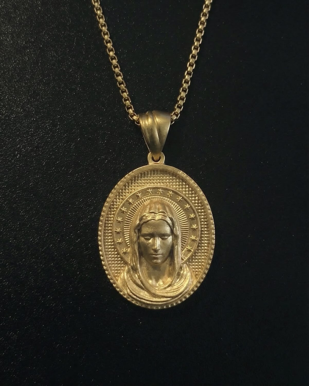 Gold Holy Mary pendant with a veiled Virgin Mary and a halo of stars on an oval medallion, close detail