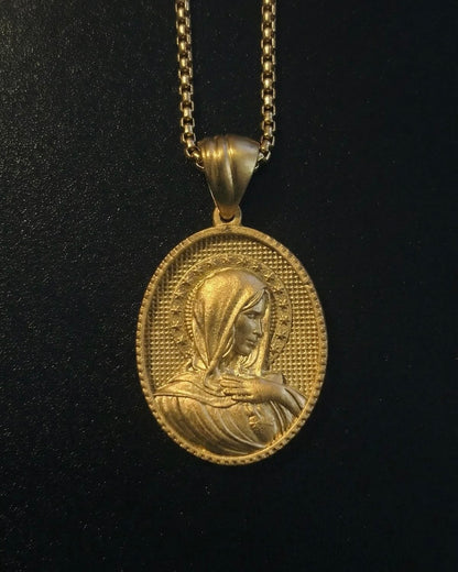 Gold Holy Mary pendant with Mary in side profile and a hand on her chest, ringed by stars, close detail