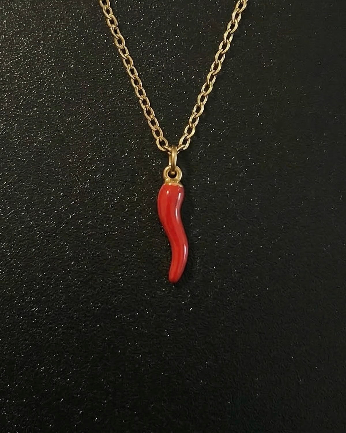 Gold Italian horn pendant in red enamel shaped into a twisted cornicello charm, close detail
