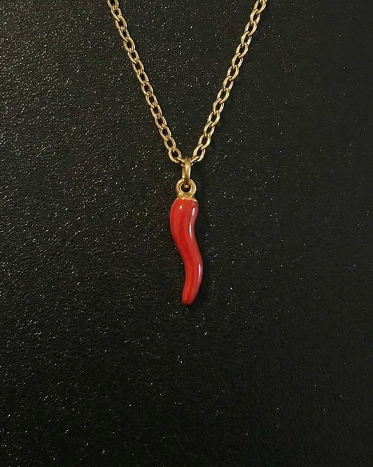 Gold Italian horn pendant in red enamel shaped into a twisted cornicello charm, close detail