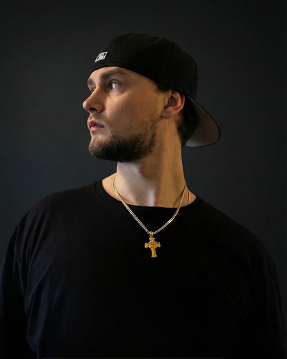 Man in a black cap and black t-shirt wearing a gold Jesus face cross necklace on a 50cm chain