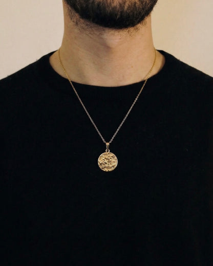 Man wearing a gold lion coin necklace on a 50cm chain over a black t-shirt