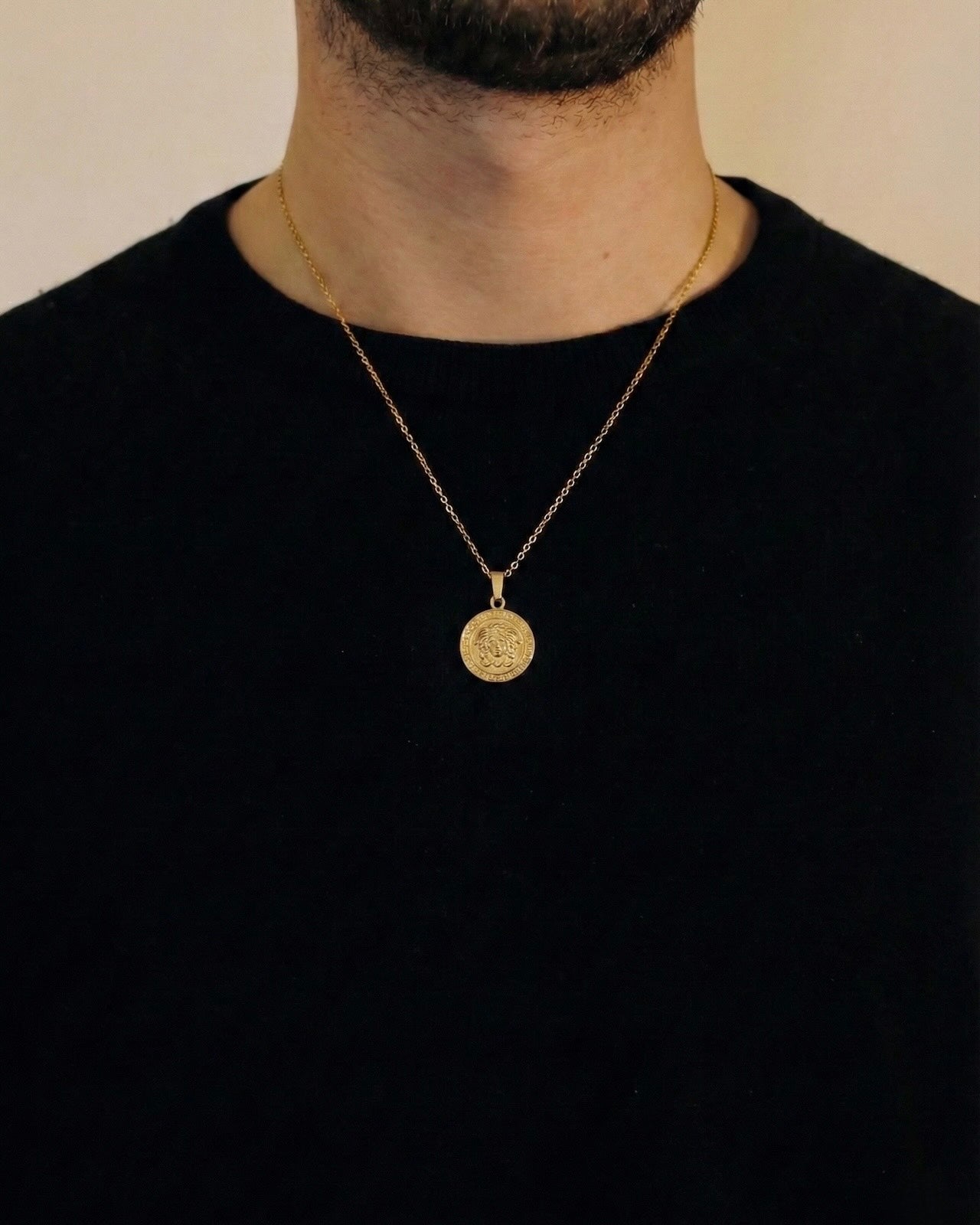 Man wearing a gold medusa necklace on a 50cm chain over a black t-shirt