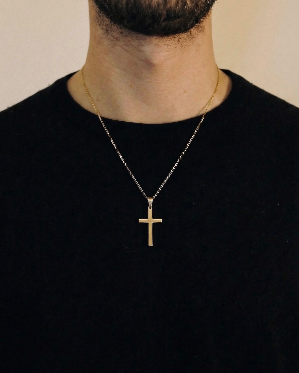 Man wearing a gold minimalist cross necklace on a 50cm chain over a black t-shirt