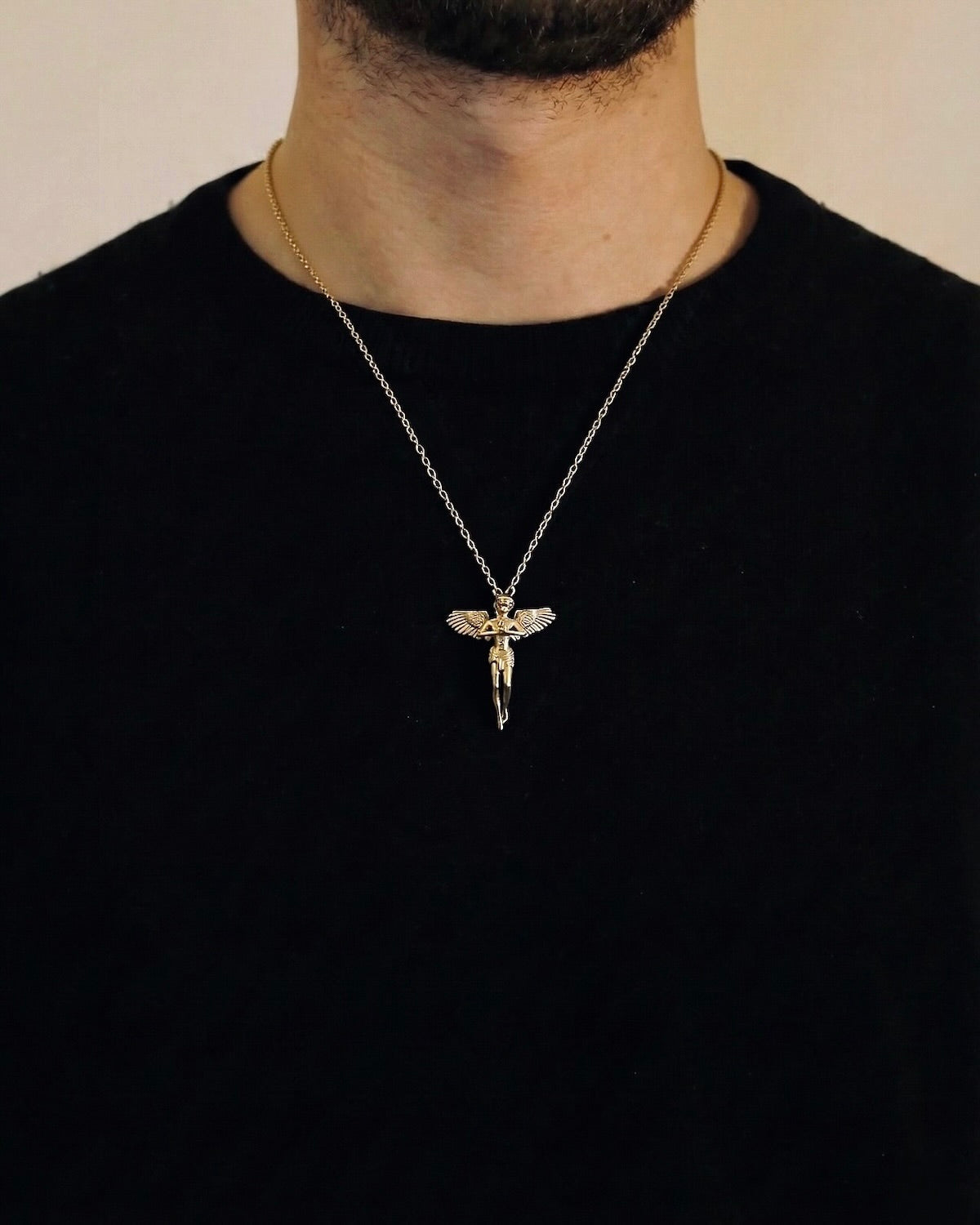 Man wearing a gold praying angel necklace on a 50cm chain over a black t-shirt