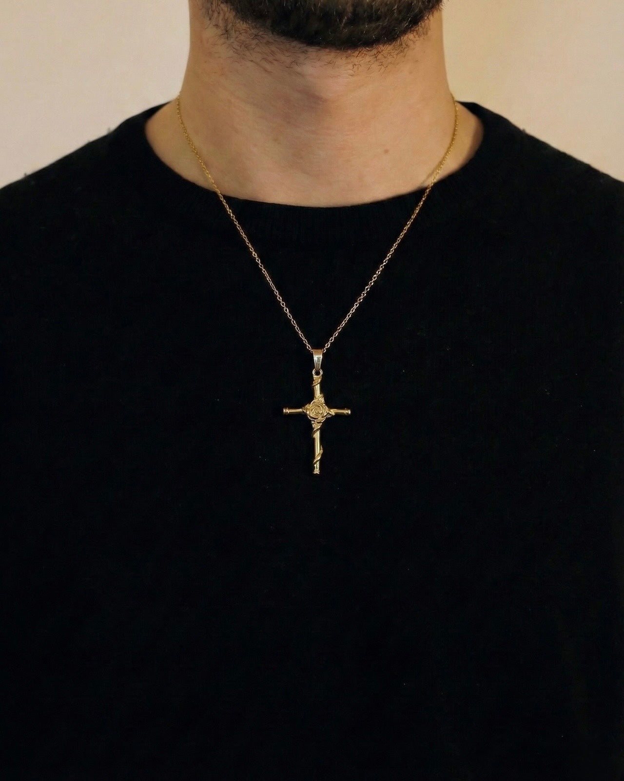 Man wearing a gold rose cross necklace on a 50cm chain over a black t-shirt