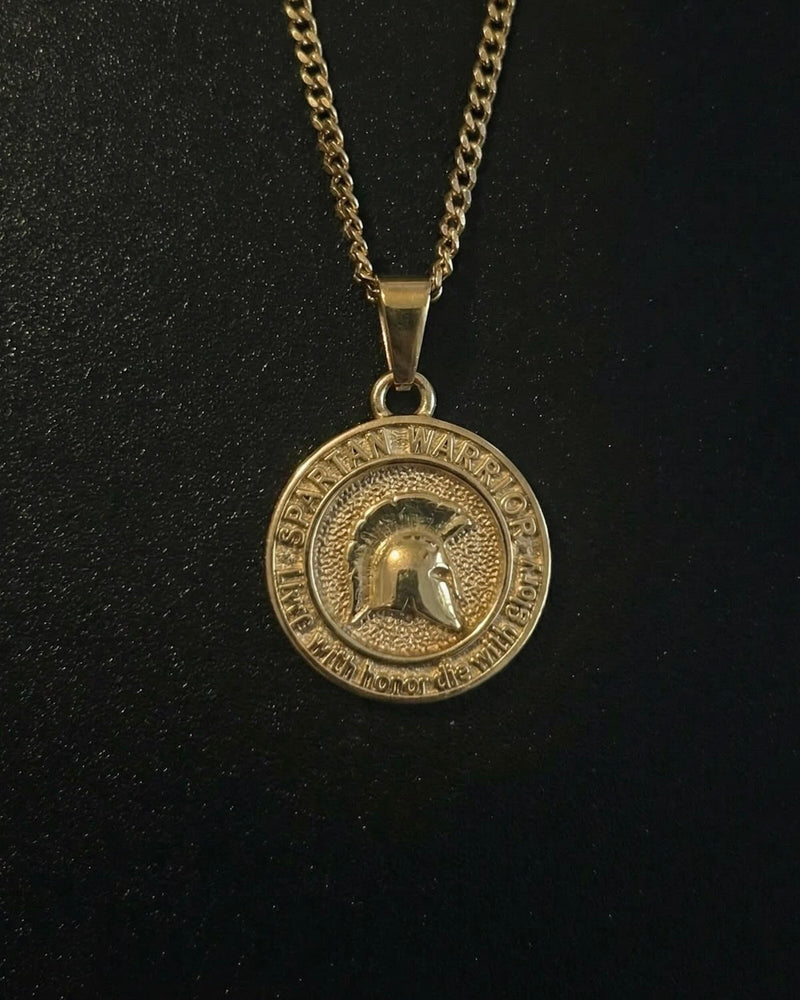 Gold Spartan warrior pendant with a helmet in profile and inscription ring, close detail