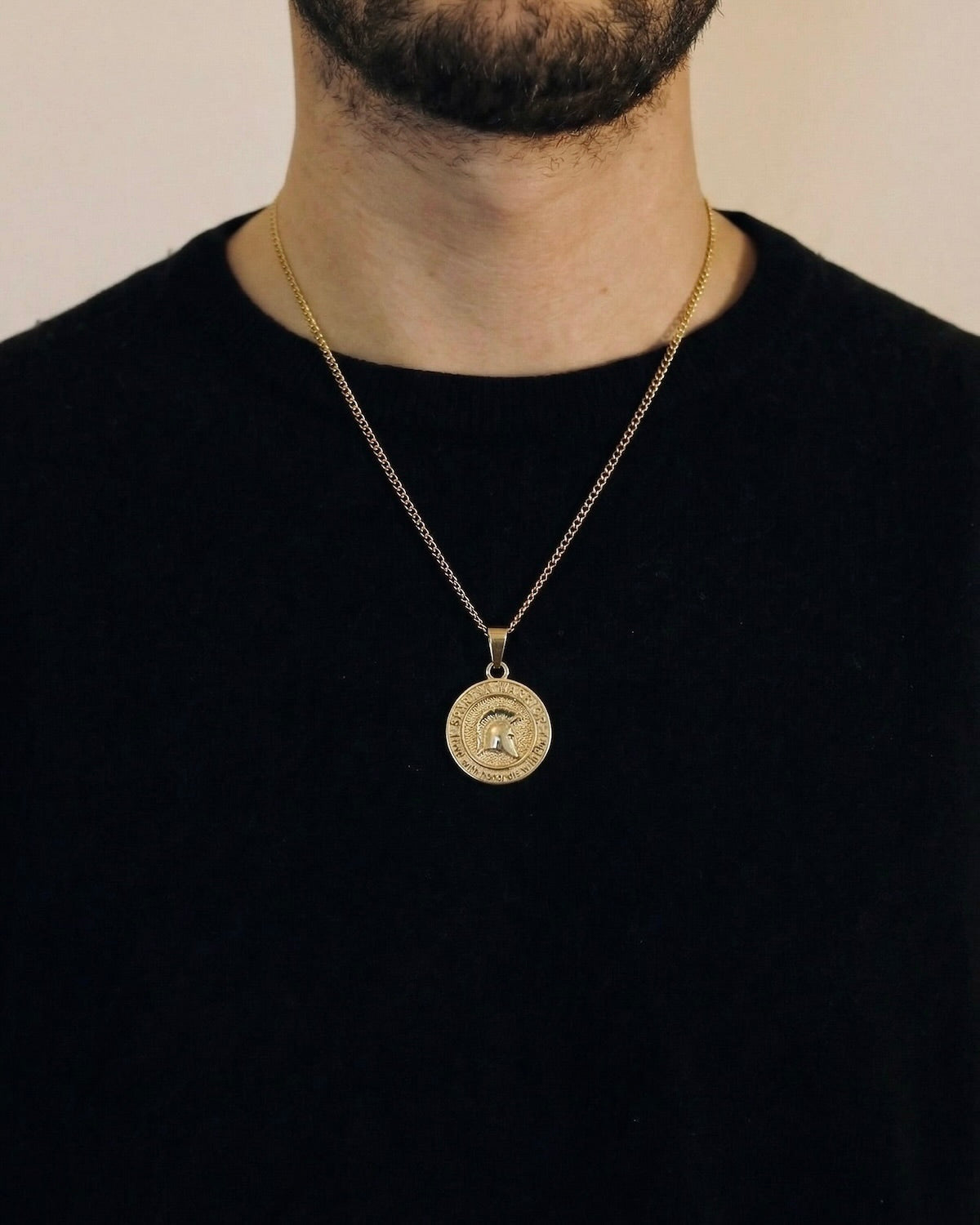 Man wearing a gold Spartan warrior necklace on a 50cm chain over a black t-shirt
