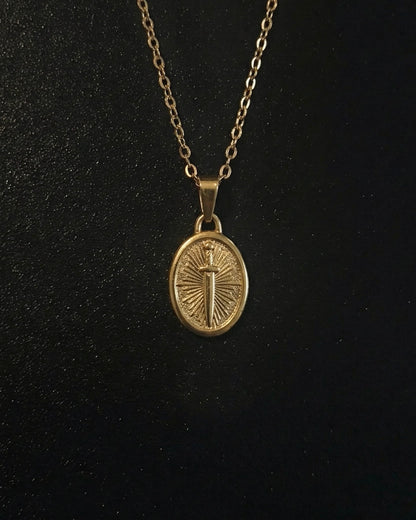 Gold sword coin pendant on an oval medallion with a dagger and sunburst, close detail