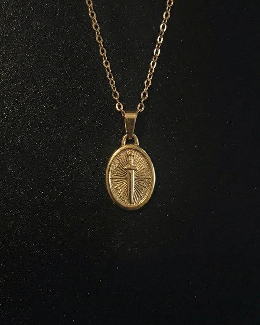 Gold sword coin pendant on an oval medallion with a dagger and sunburst, close detail