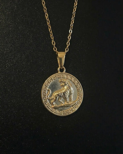 Gold tiger coin pendant with a roaring tiger and Greek key border, close detail