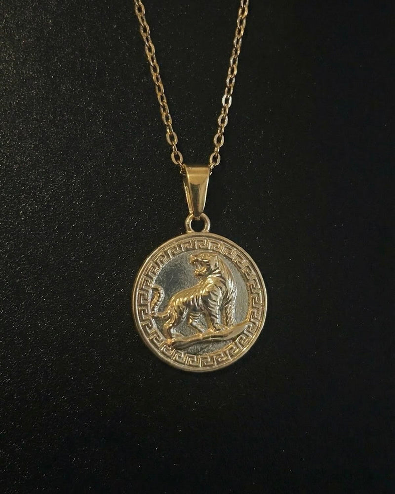 Gold tiger coin pendant with a roaring tiger and Greek key border, close detail