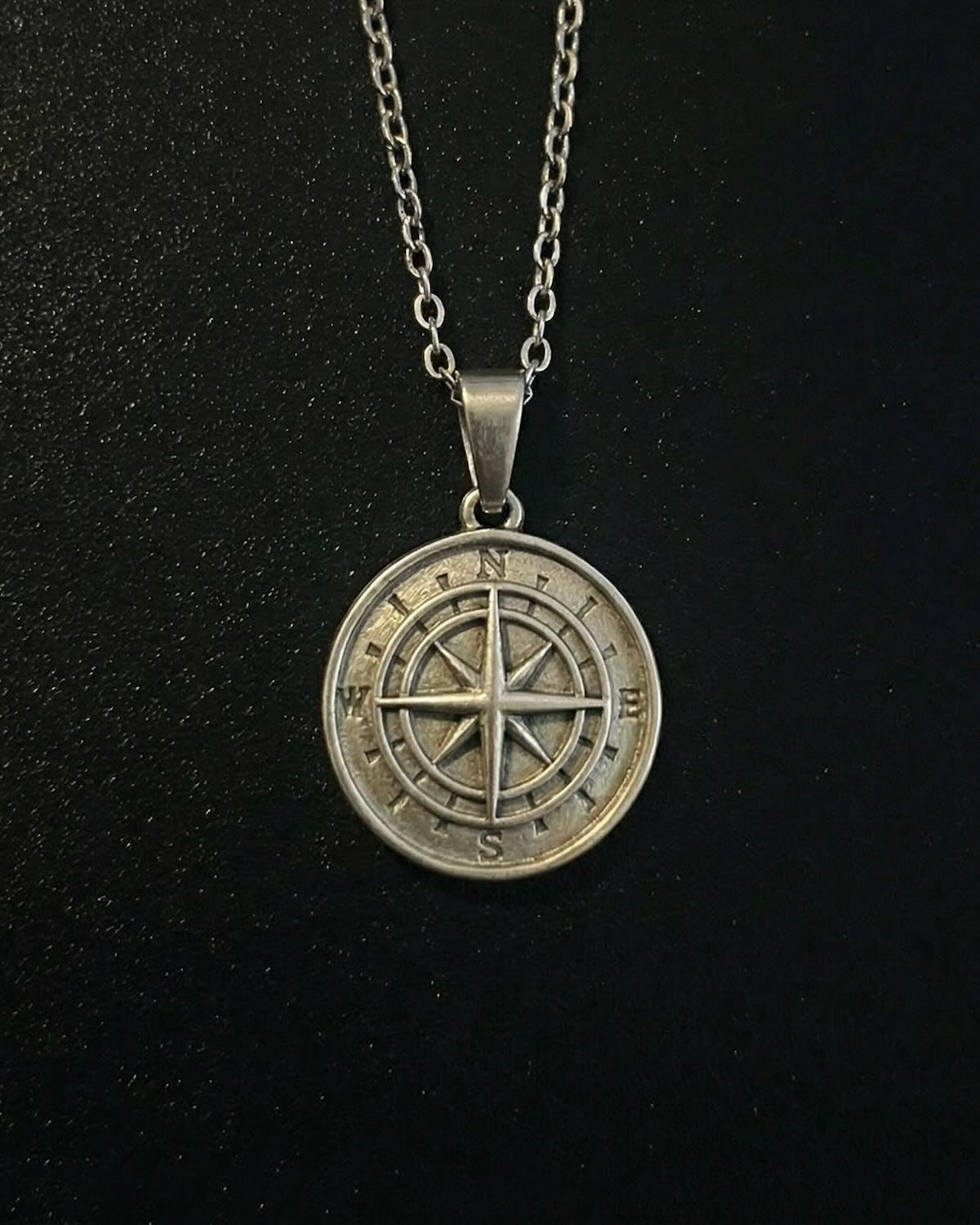 Silver compass pendant with a compass rose and eight-point star, close detail