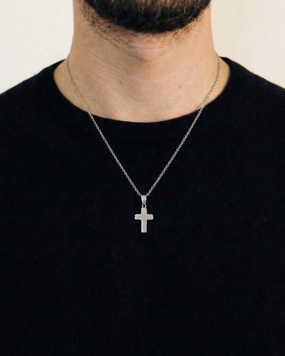 Man wearing a silver cross necklace on a 50cm chain over a black t-shirt