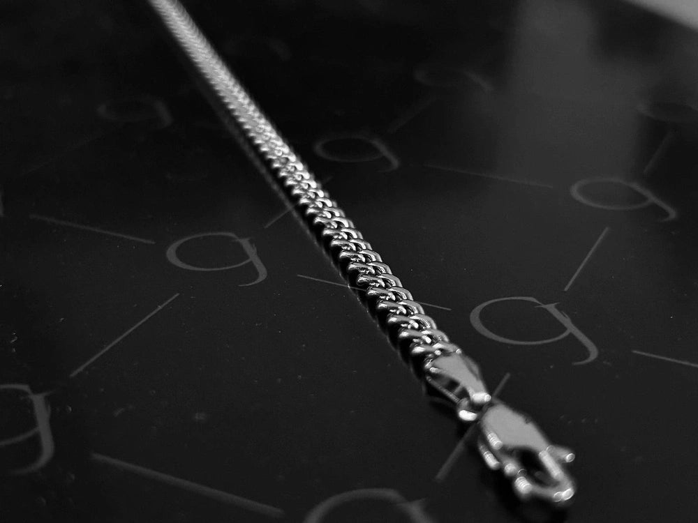 4mm silver stainless steel Cuban link chain with lobster clasp on a dark background