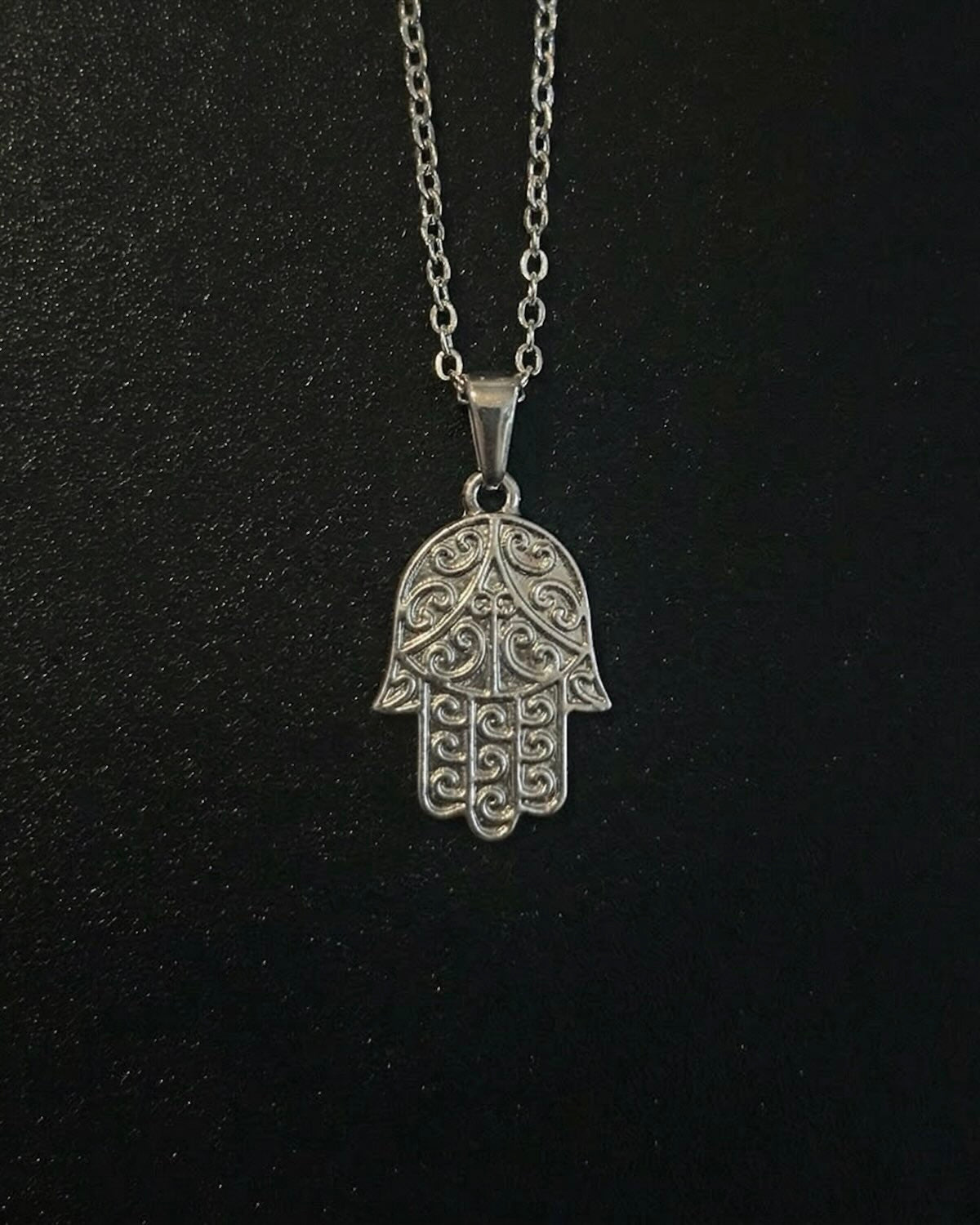 Silver hamsa hand pendant with detailed filigree scrollwork, close detail