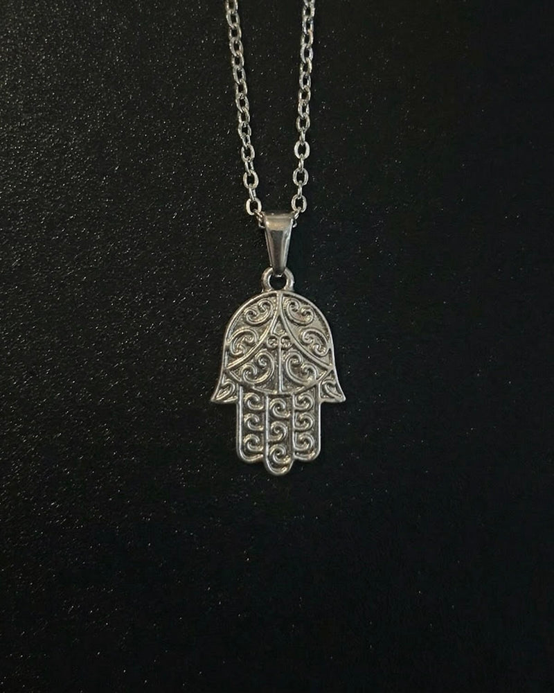 Silver hamsa hand pendant with detailed filigree scrollwork, close detail