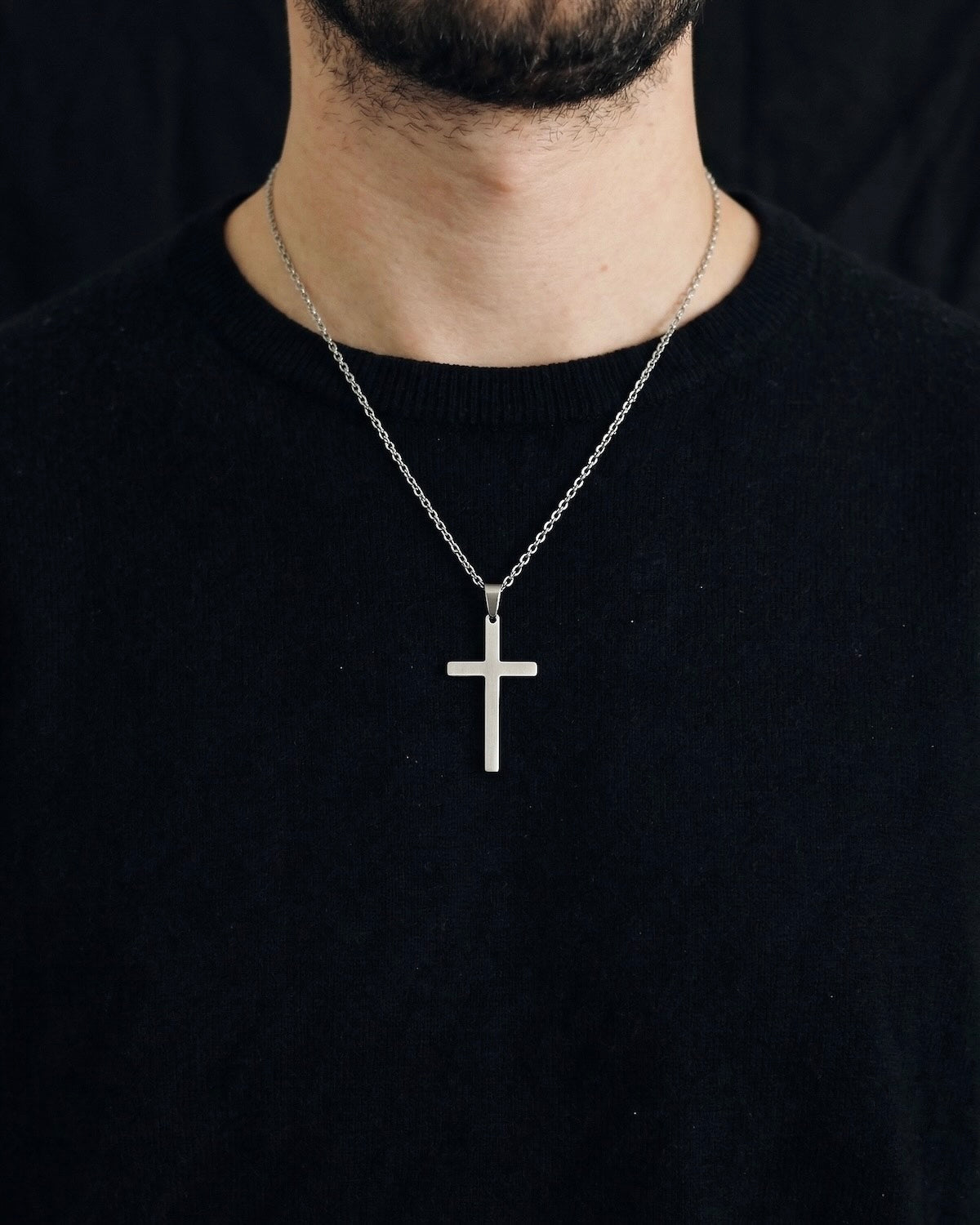 Man wearing a silver minimalist cross necklace on a 50cm chain over a black t-shirt