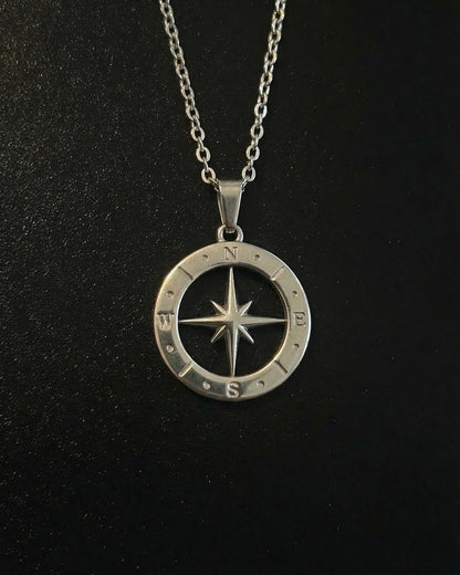 Silver open compass pendant with a cut-out star inside a ring of compass markings, close detail