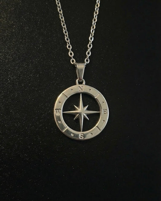 Silver open compass pendant with a cut-out star inside a ring of compass markings, close detail