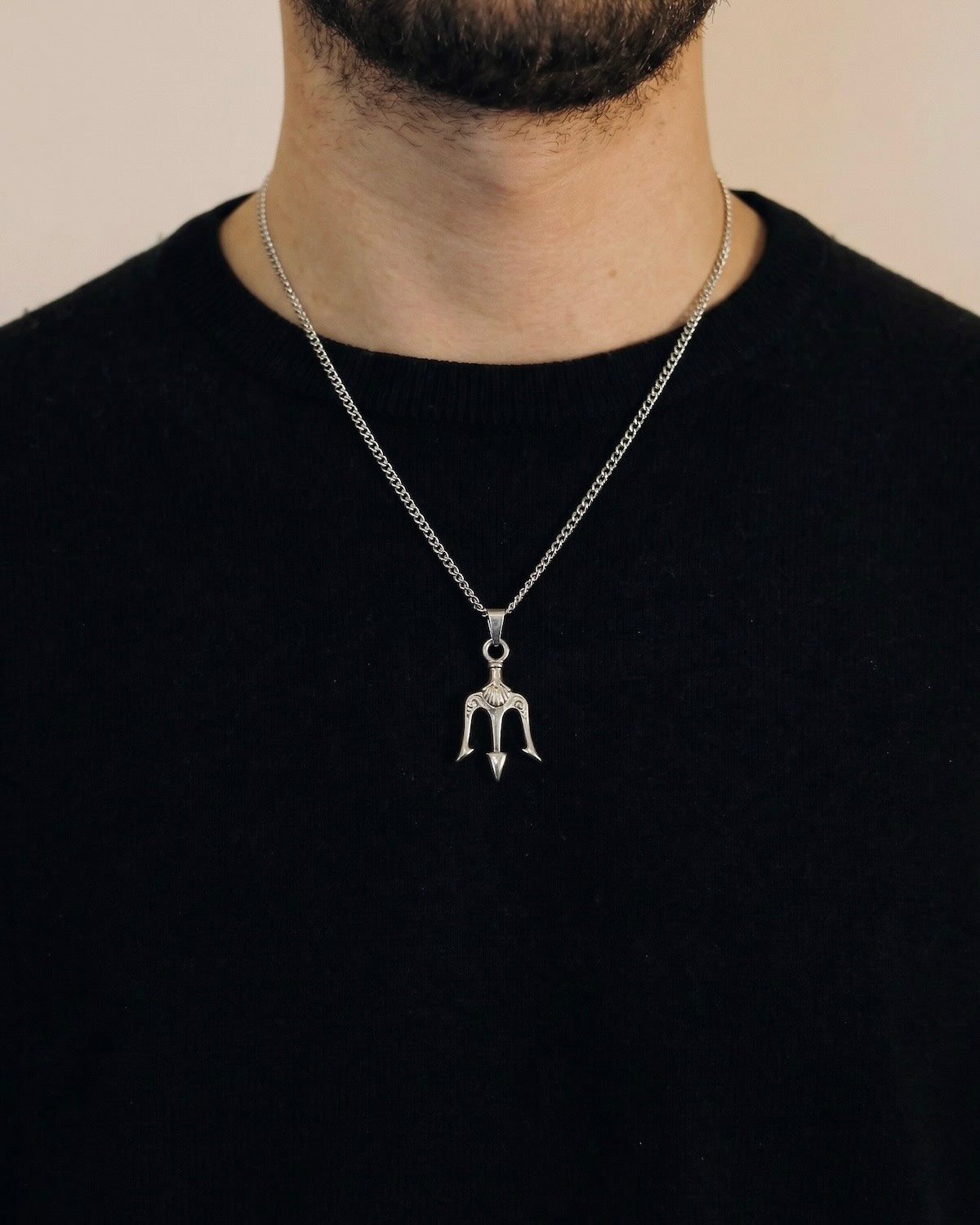 Man wearing a silver trident necklace on a 50cm chain over a black t-shirt