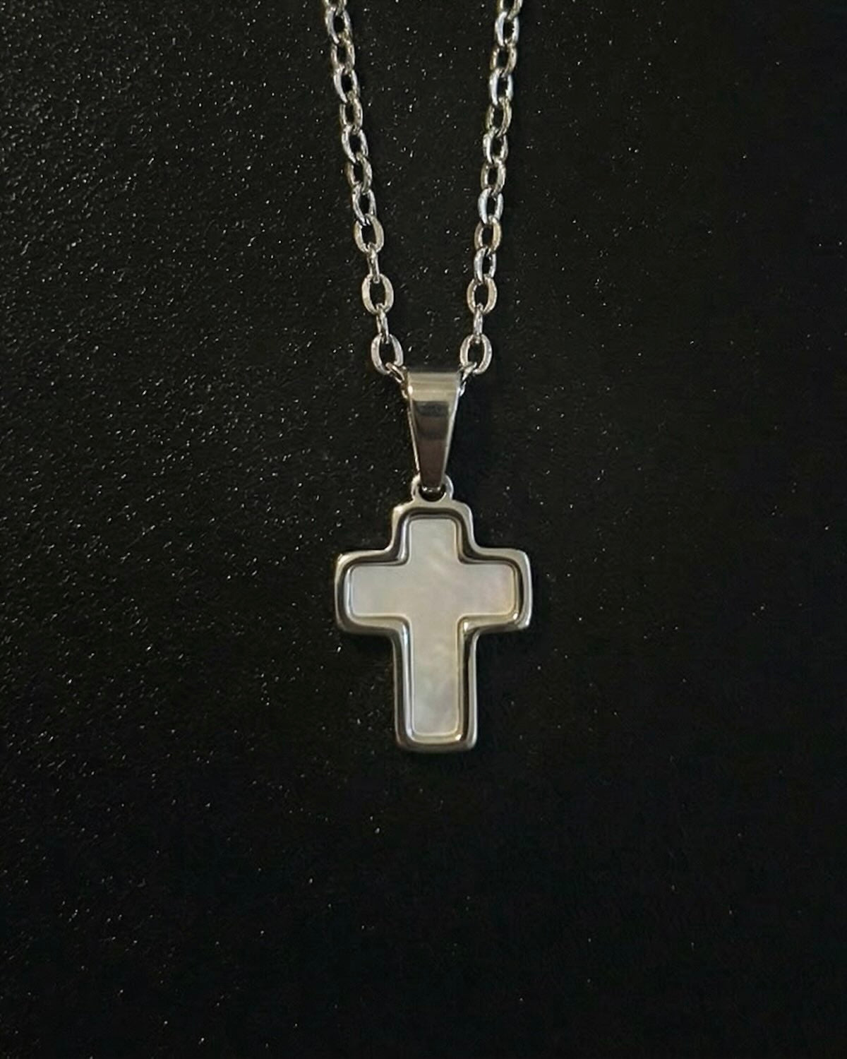 Silver trimmed cross pendant with a steel frame and mother-of-pearl center, close detail