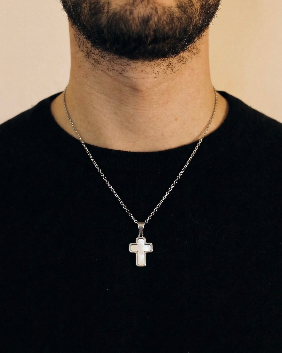 Man wearing a silver trimmed cross necklace on a 50cm chain over a black t-shirt